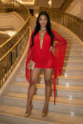 Woman in a red outfit standing on a staircase in an elegant interior setting