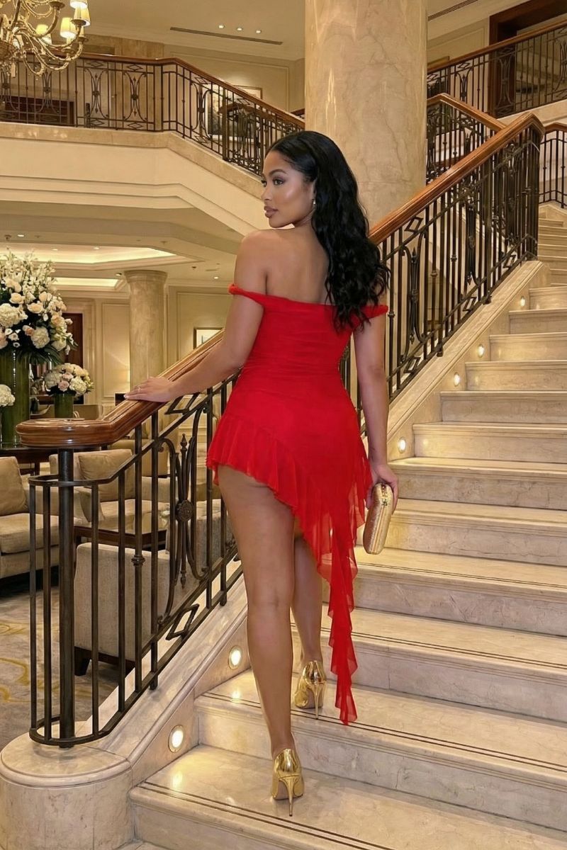 Woman in a red dress walking down a staircase in an elegant interior setting